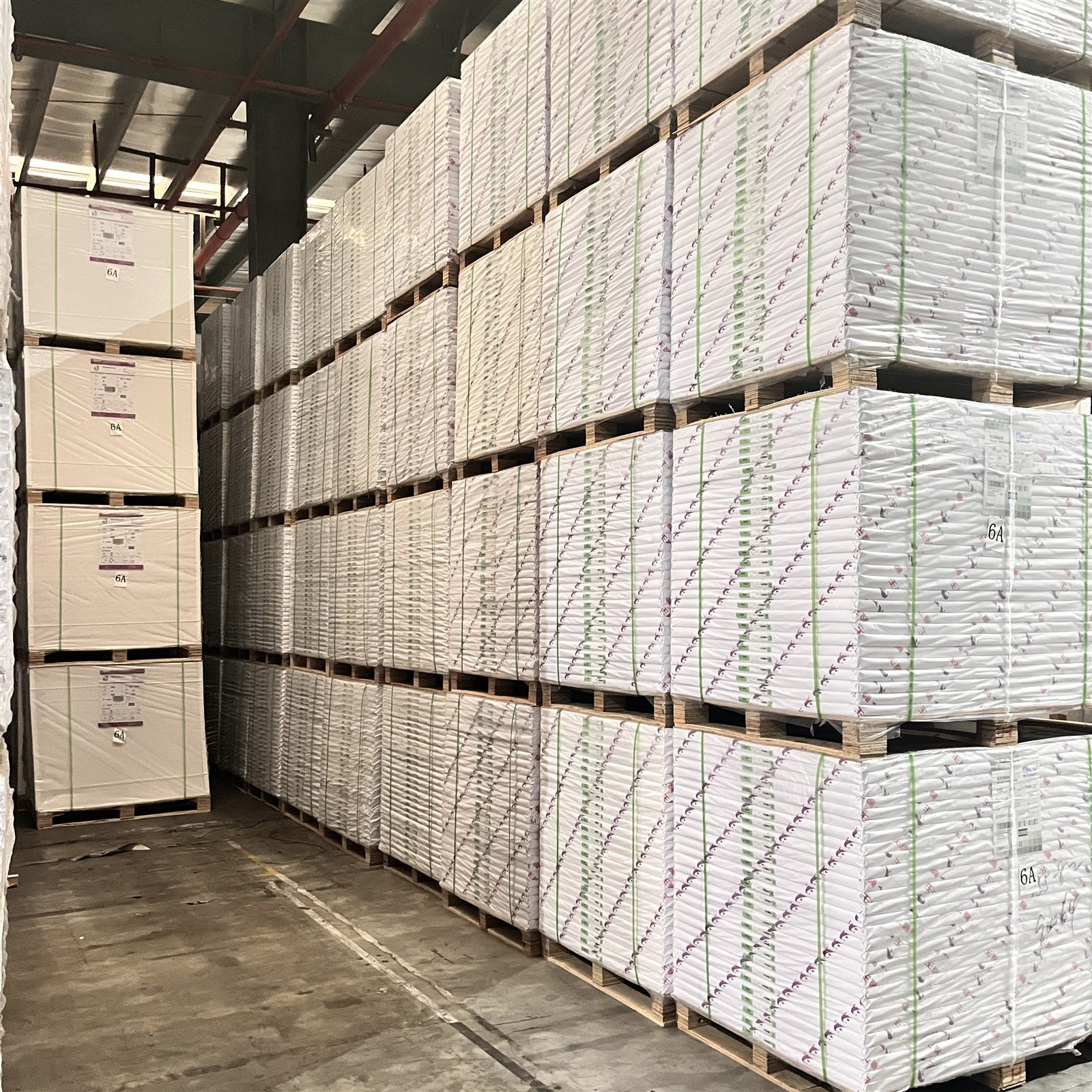 Export-ready palletised offset paper stored in a warehouse aisle